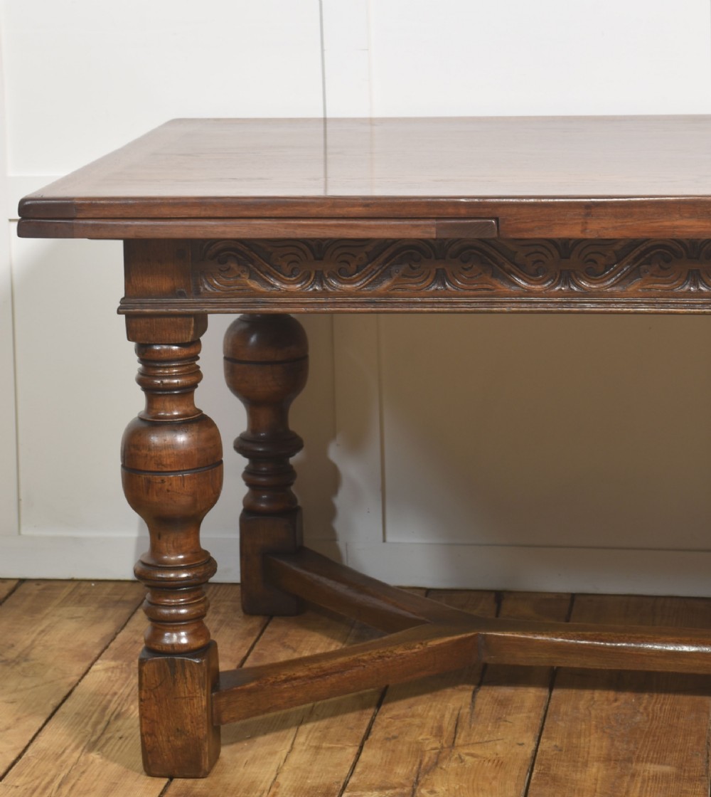 An extended dark oak Jacobean style dining table featuring carved friezes, turned baluster legs, and a sturdy stretcher base. View VIII