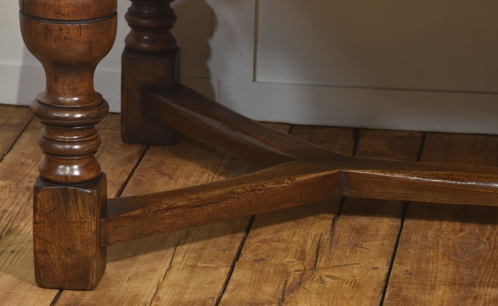 An extended dark oak Jacobean style dining table featuring carved friezes, turned baluster legs, and a sturdy stretcher base. View IX