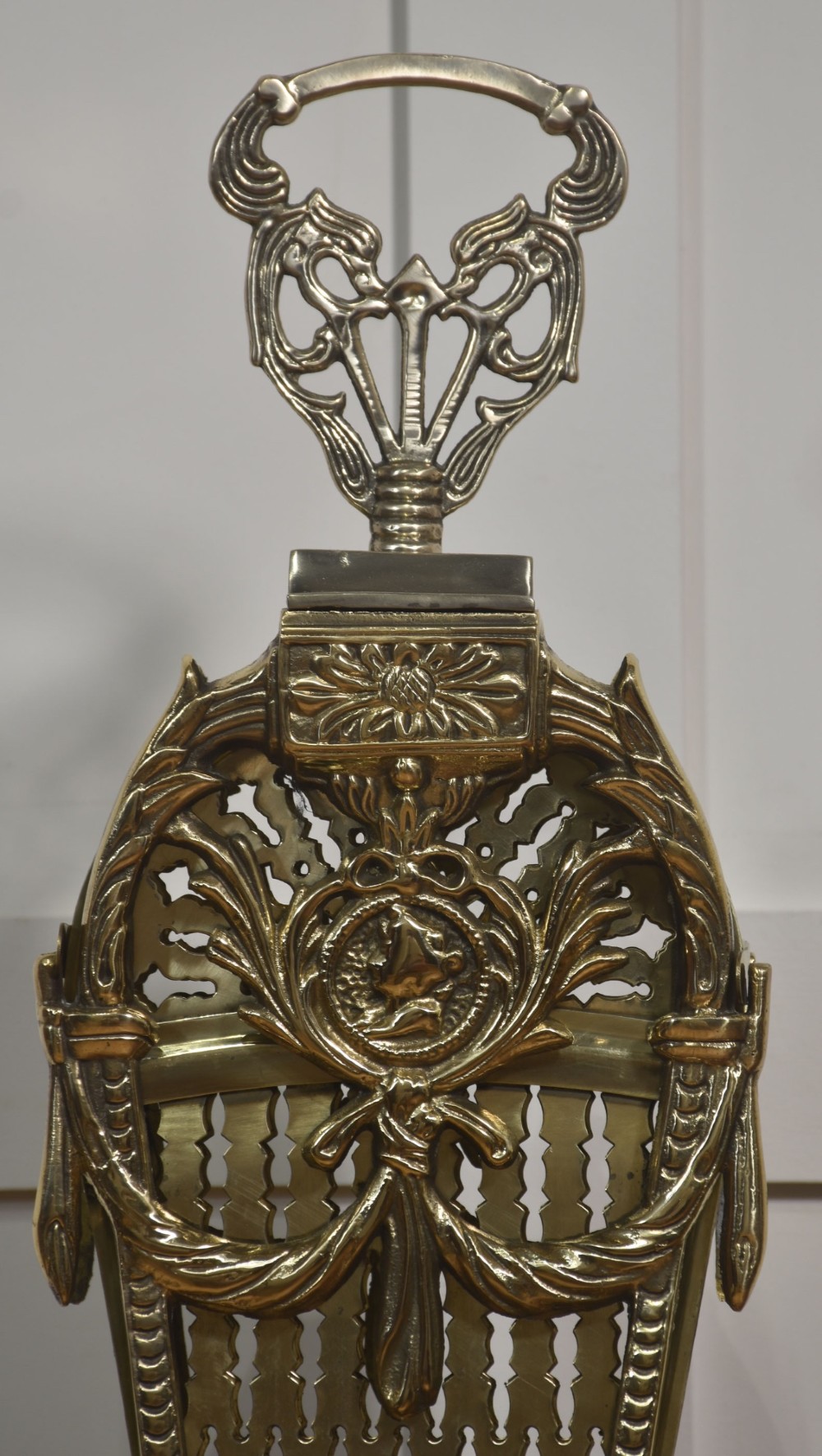 A Victorian brass peacock fire screen with pierced filigree fan blades expanding from a cast metal pedestal base. View IV