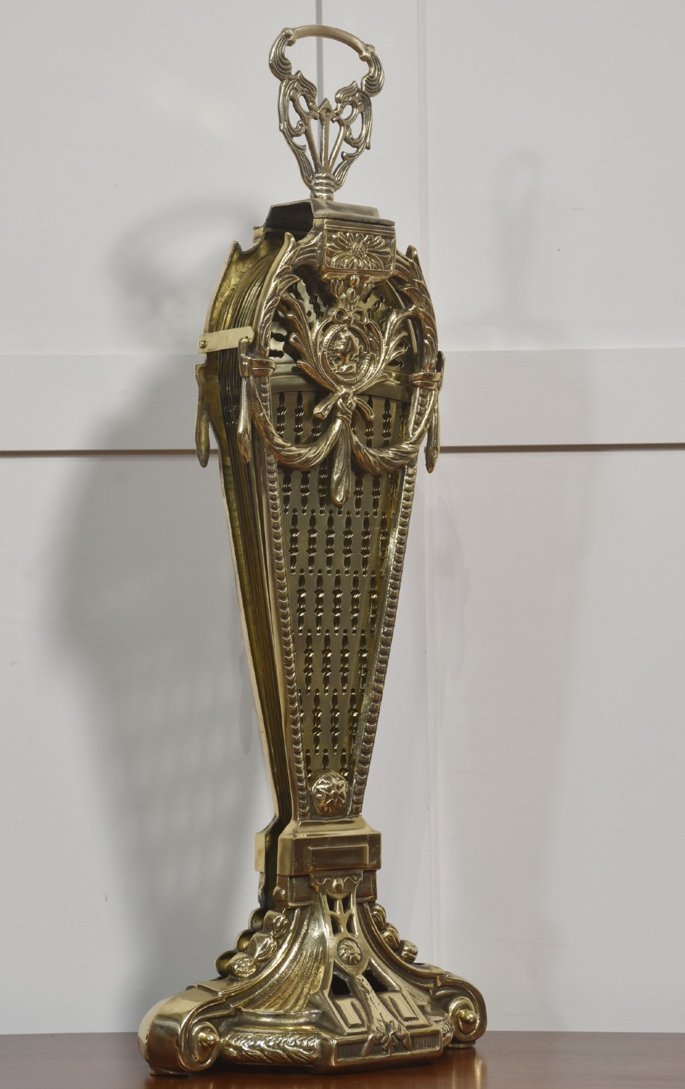 A Victorian brass peacock fire screen with pierced filigree fan blades expanding from a cast metal pedestal base. View V