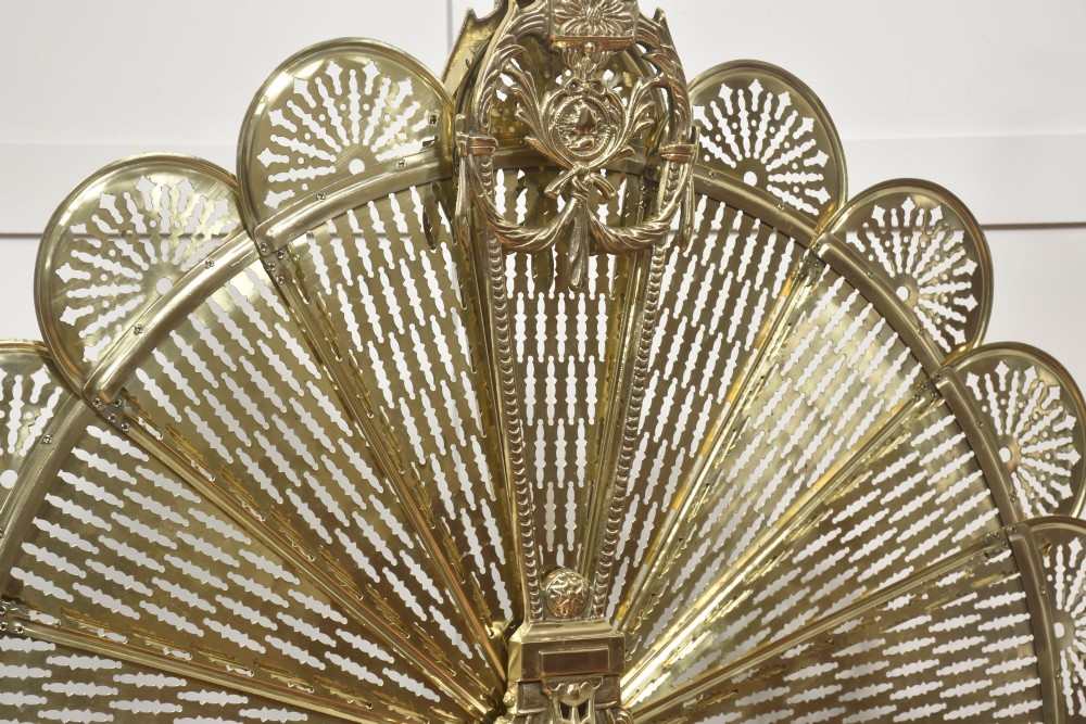 A Victorian brass peacock fire screen with pierced filigree fan blades expanding from a cast metal pedestal base. View XI