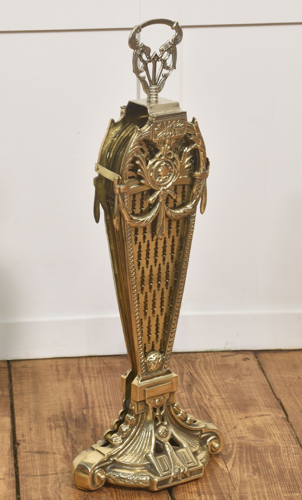 A Victorian brass peacock fire screen with pierced filigree fan blades expanding from a cast metal pedestal base. View XII