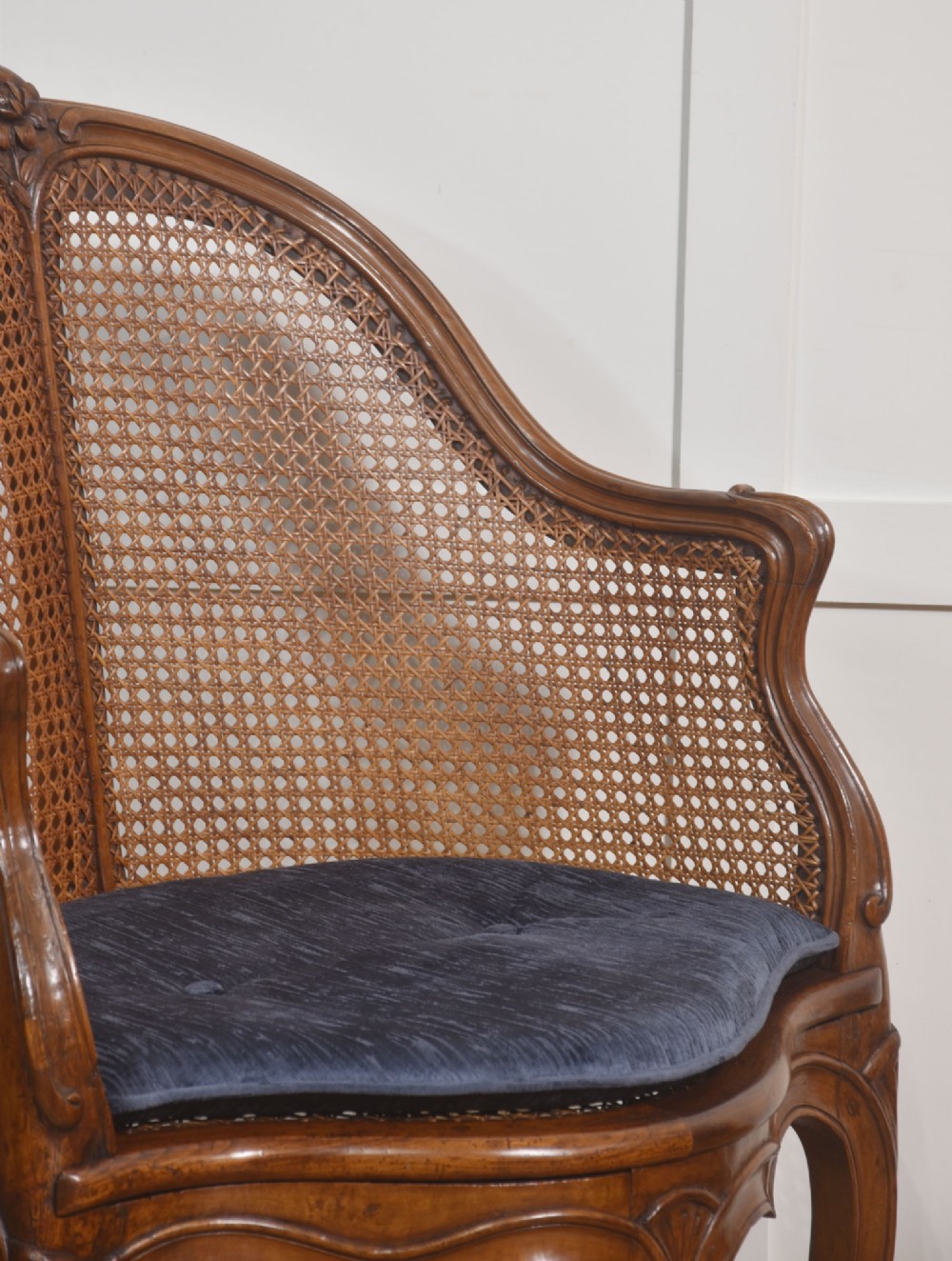A 19th-century French Louis XV style carved walnut corner tub chair with a woven cane backrest and curved cabriole legs. View V