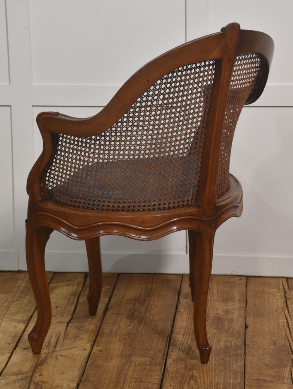 A 19th-century French Louis XV style carved walnut corner tub chair with a woven cane backrest and curved cabriole legs. View IX