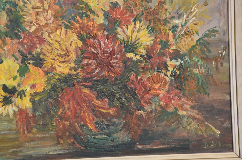 An oil painting depicting a dense arrangement of yellow, red, and orange flowers in a bowl, set within a light cream wooden frame. View V