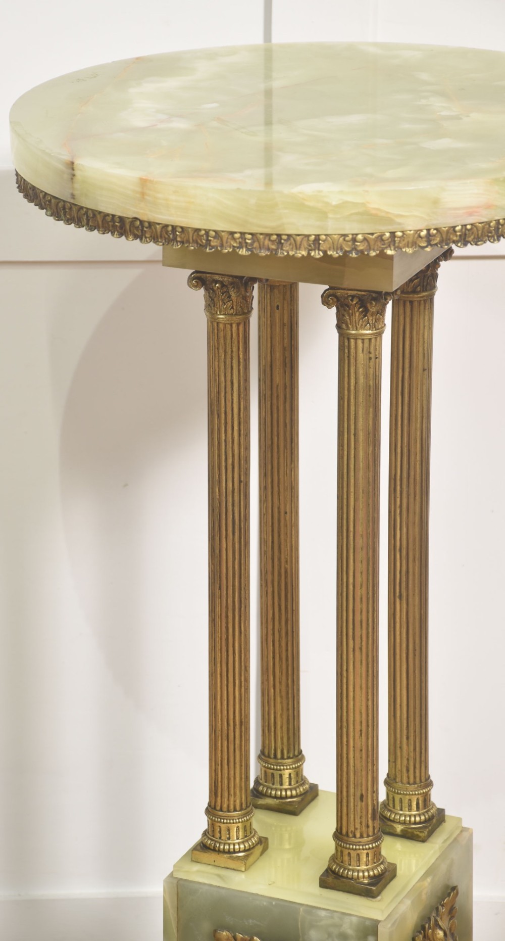 A Neoclassical circular green onyx pedestal table supported by four fluted gilt brass columns on a stepped plinth base. View IV