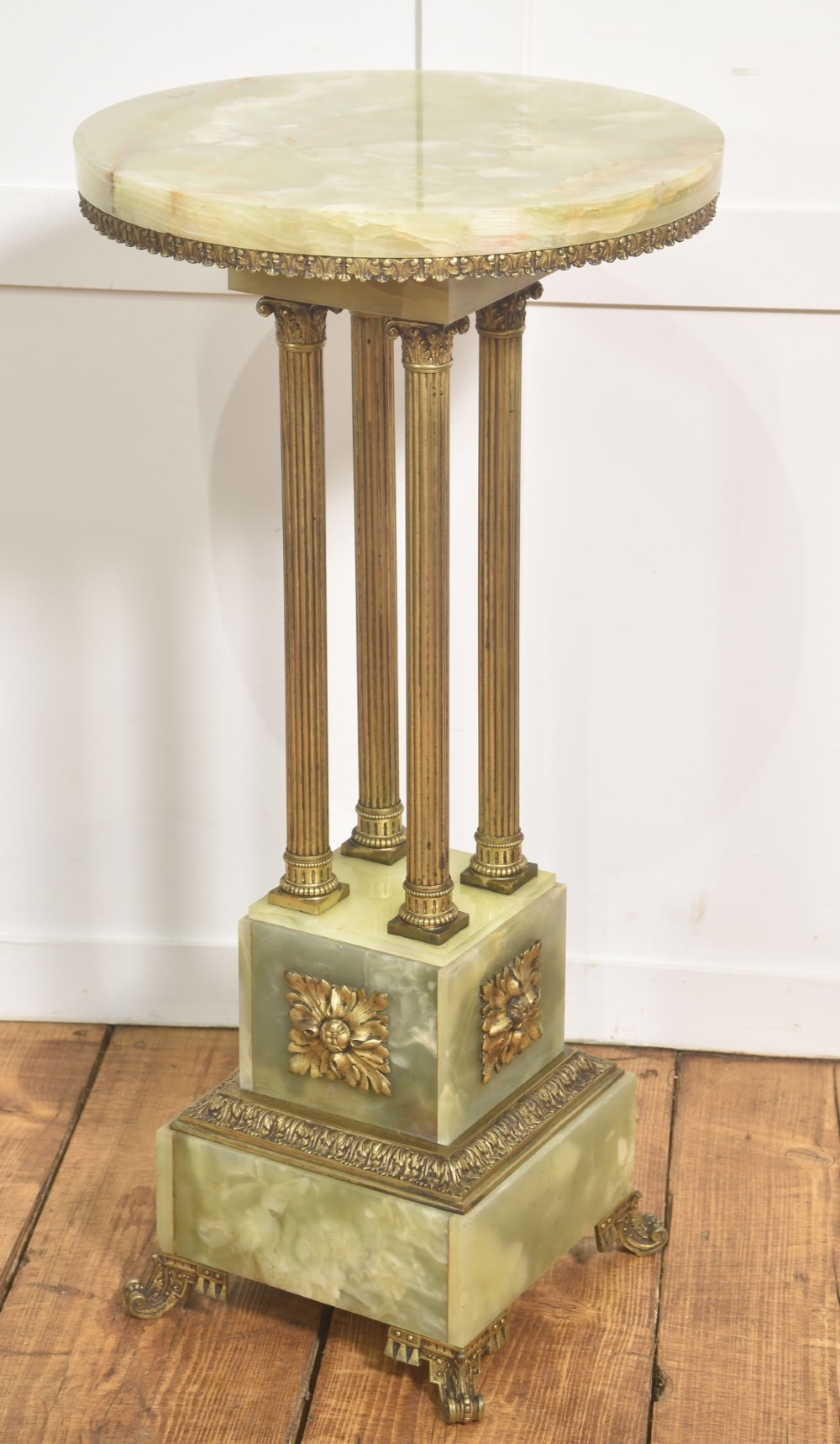 A Neoclassical circular green onyx pedestal table supported by four fluted gilt brass columns on a stepped plinth base. View V