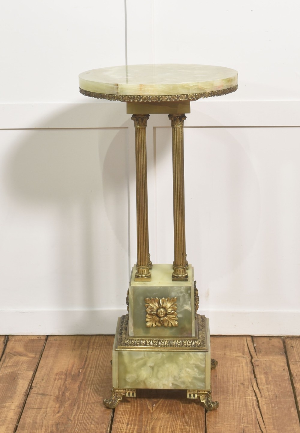 A Neoclassical circular green onyx pedestal table supported by four fluted gilt brass columns on a stepped plinth base.