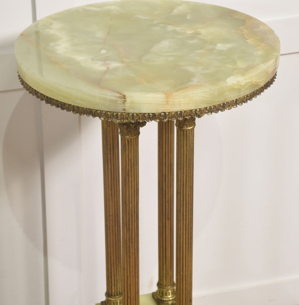 A Neoclassical circular green onyx pedestal table supported by four fluted gilt brass columns on a stepped plinth base. View IX