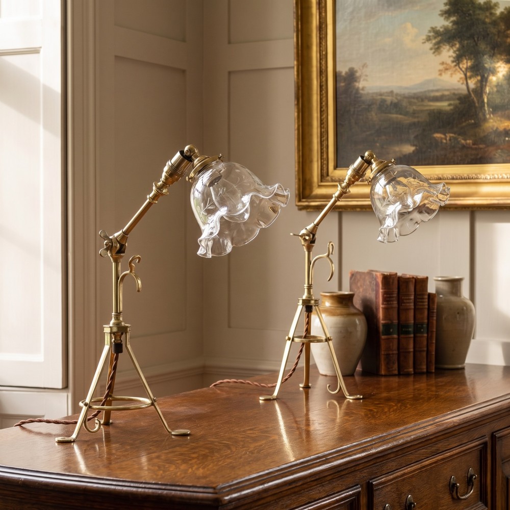 A pair of antique brass adjustable lamps featuring tripod bases with pad feet, central articulated joints with wing nuts, and tilting bulb holders. View II
