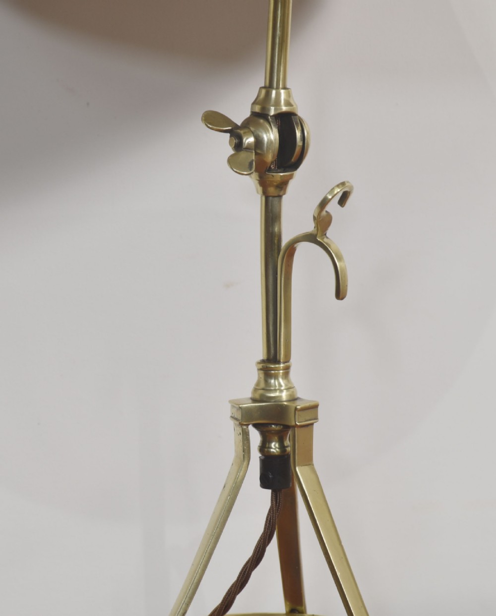 A pair of antique brass adjustable lamps featuring tripod bases with pad feet, central articulated joints with wing nuts, and tilting bulb holders. View VI