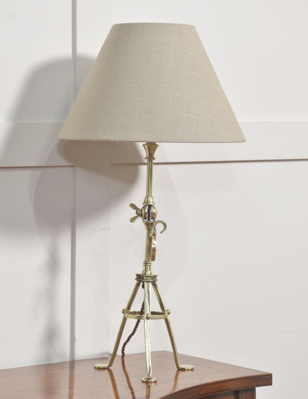 A pair of antique brass adjustable lamps featuring tripod bases with pad feet, central articulated joints with wing nuts, and tilting bulb holders. View VII