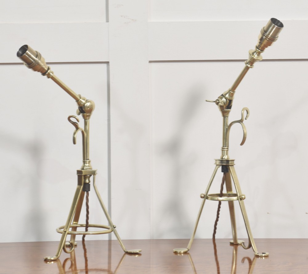 A pair of antique brass adjustable lamps featuring tripod bases with pad feet, central articulated joints with wing nuts, and tilting bulb holders. View VIII