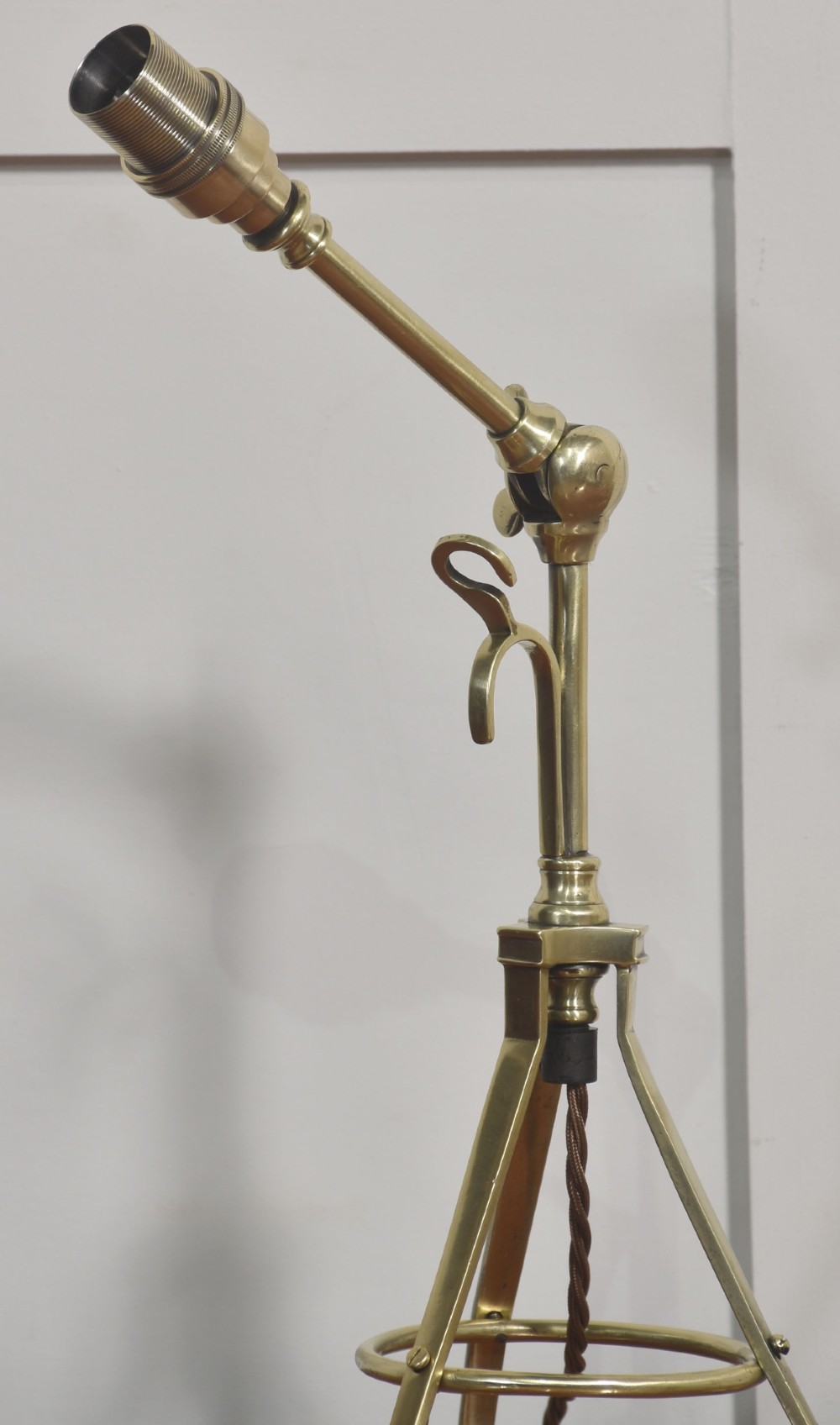 A pair of antique brass adjustable lamps featuring tripod bases with pad feet, central articulated joints with wing nuts, and tilting bulb holders. View X