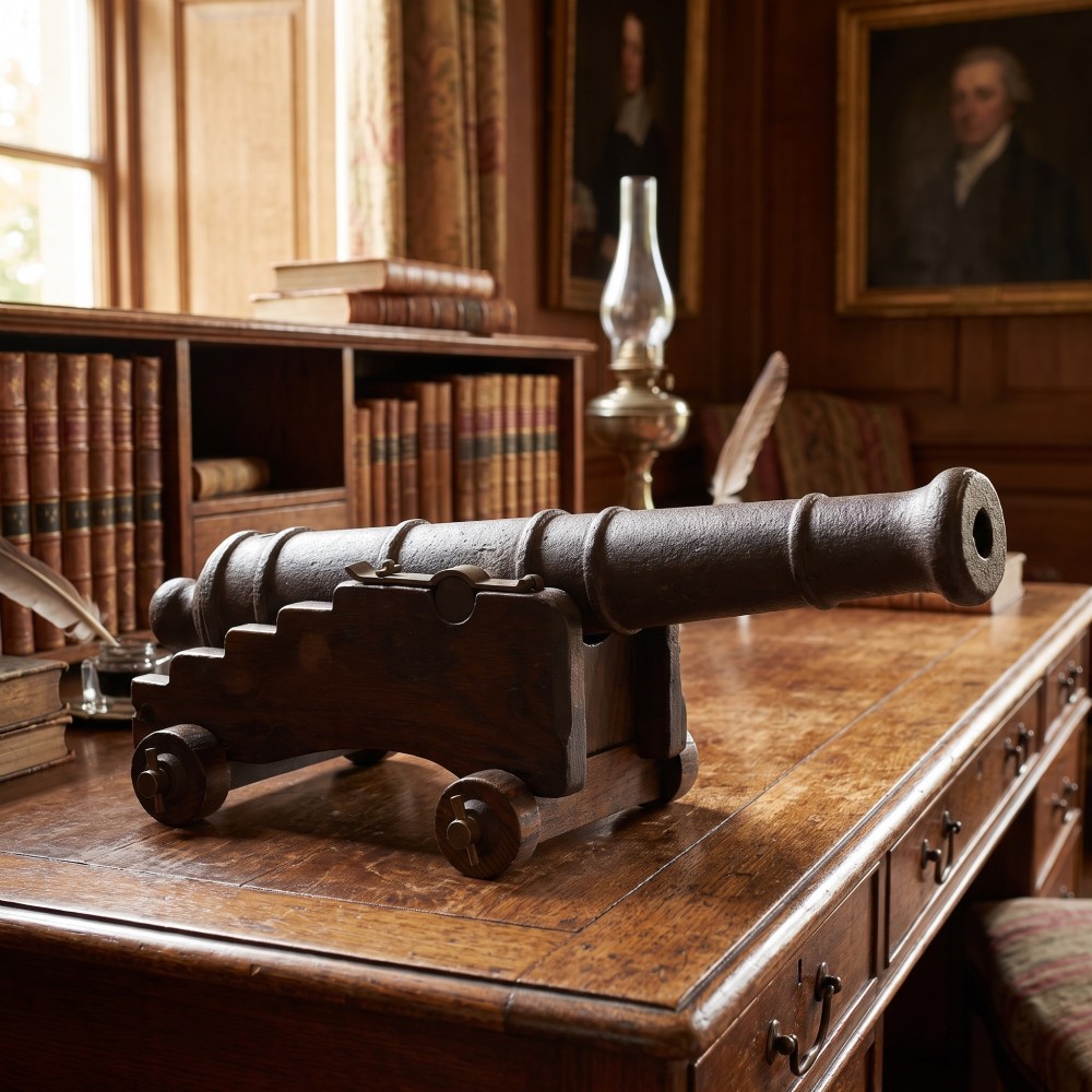 A 19th-century cast iron signal cannon mounted on a stepped dark oak carriage with wooden wheels. View II