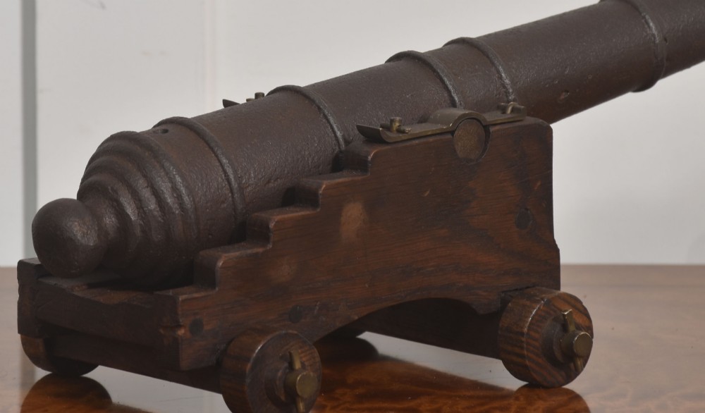 A 19th-century cast iron signal cannon mounted on a stepped dark oak carriage with wooden wheels. View III