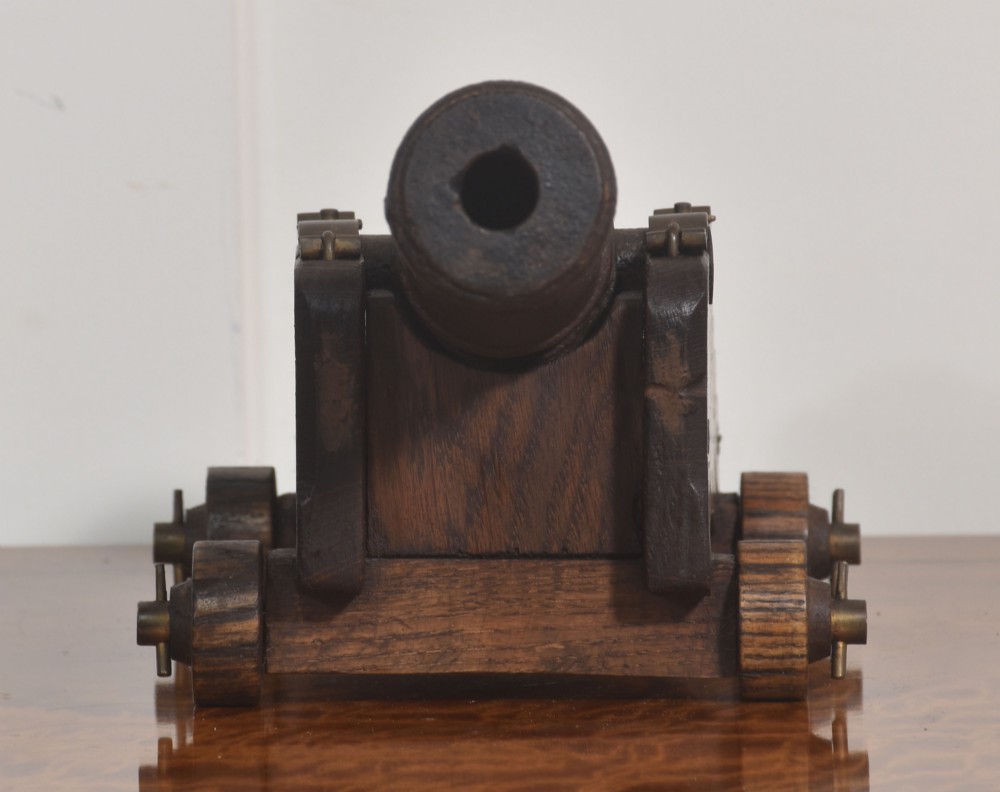 A 19th-century cast iron signal cannon mounted on a stepped dark oak carriage with wooden wheels. View V