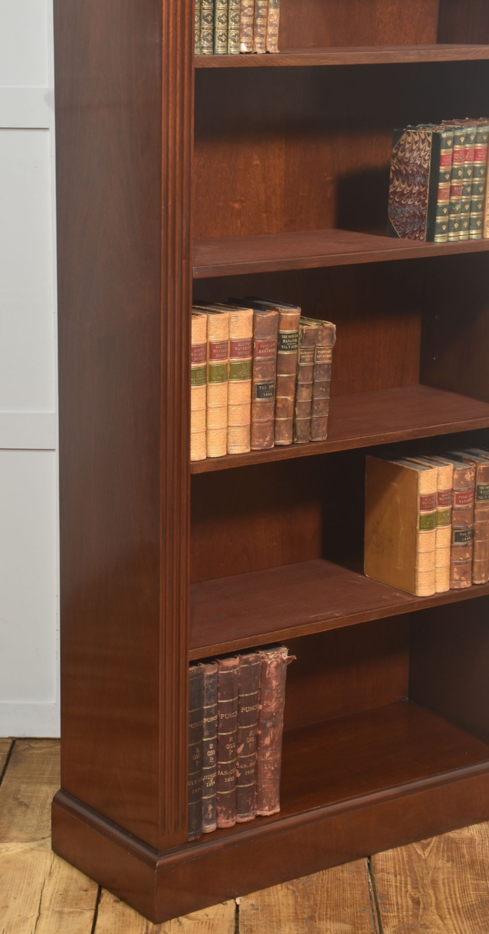 A tall mahogany open bookcase featuring adjustable shelves, fluted side pilasters, and a carved geometric frieze beneath a moulded cornice. View VI