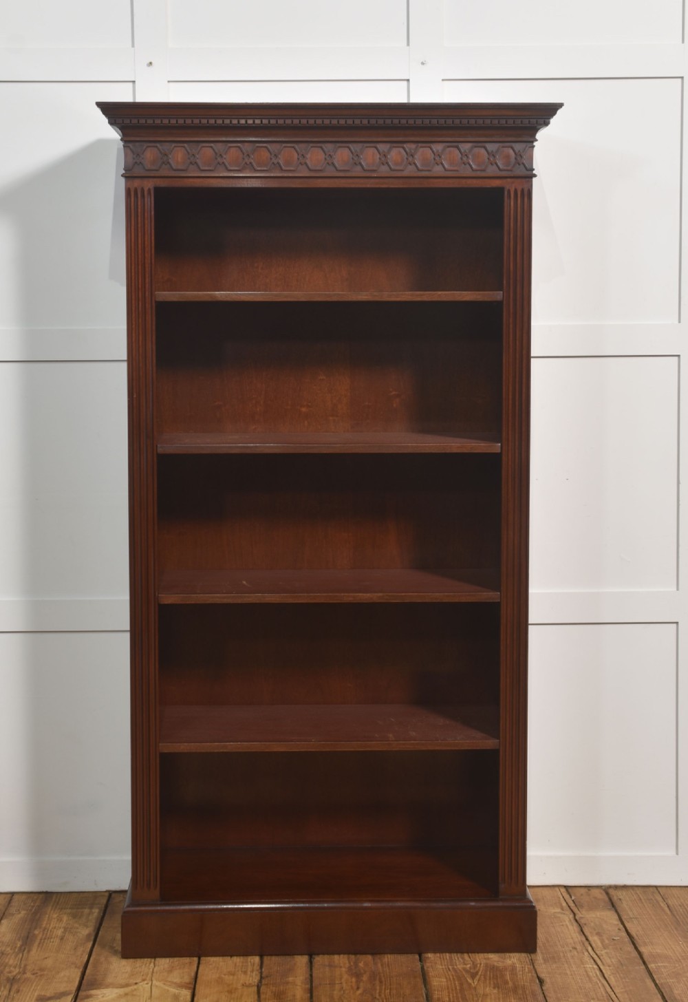 A tall mahogany open bookcase featuring adjustable shelves, fluted side pilasters, and a carved geometric frieze beneath a moulded cornice. View VIII