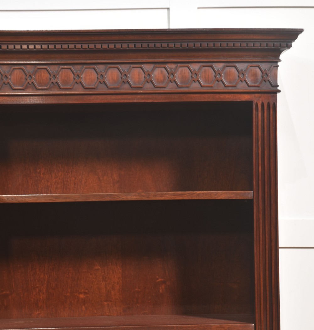 A tall mahogany open bookcase featuring adjustable shelves, fluted side pilasters, and a carved geometric frieze beneath a moulded cornice. View IX