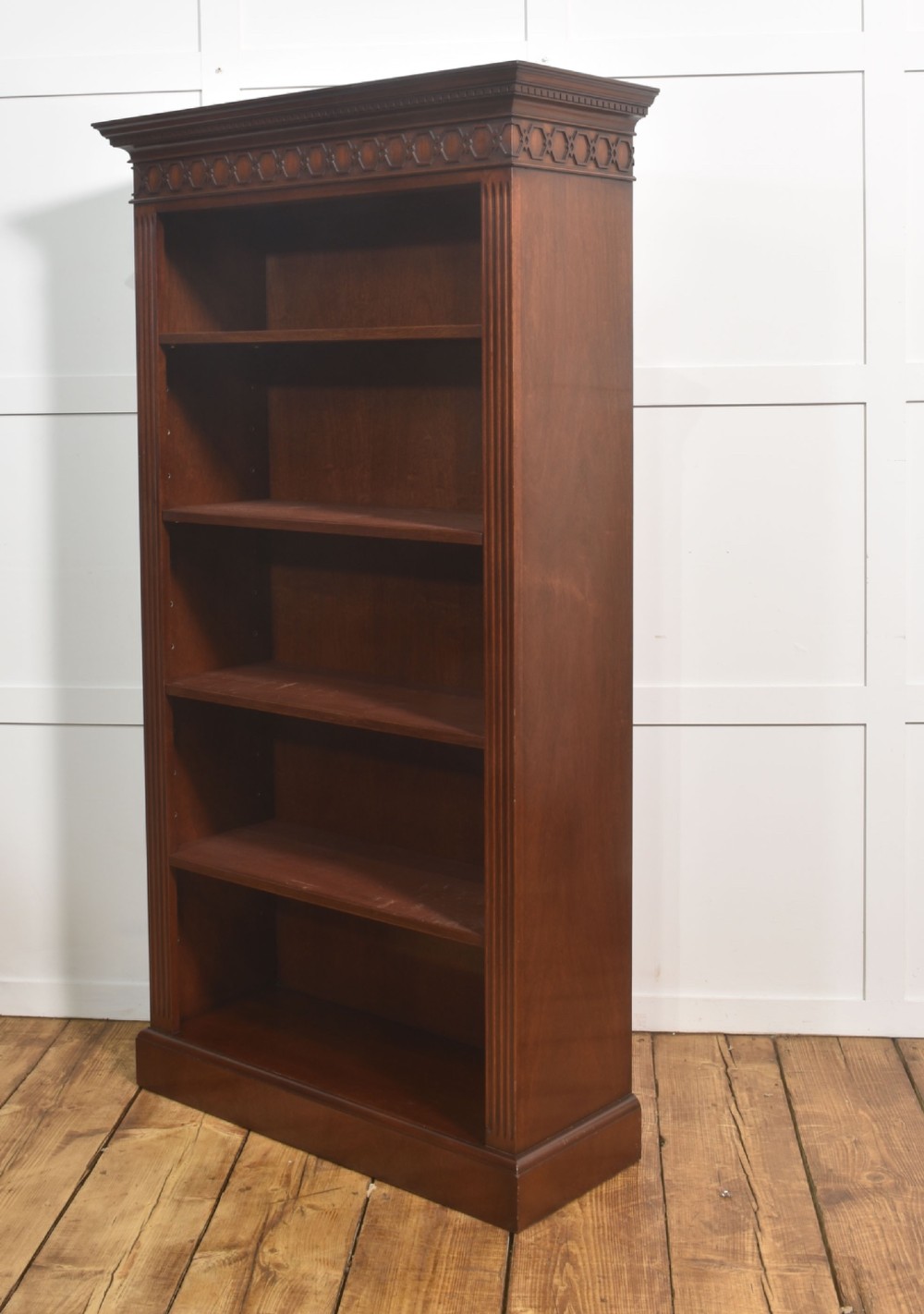 A tall mahogany open bookcase featuring adjustable shelves, fluted side pilasters, and a carved geometric frieze beneath a moulded cornice. View X