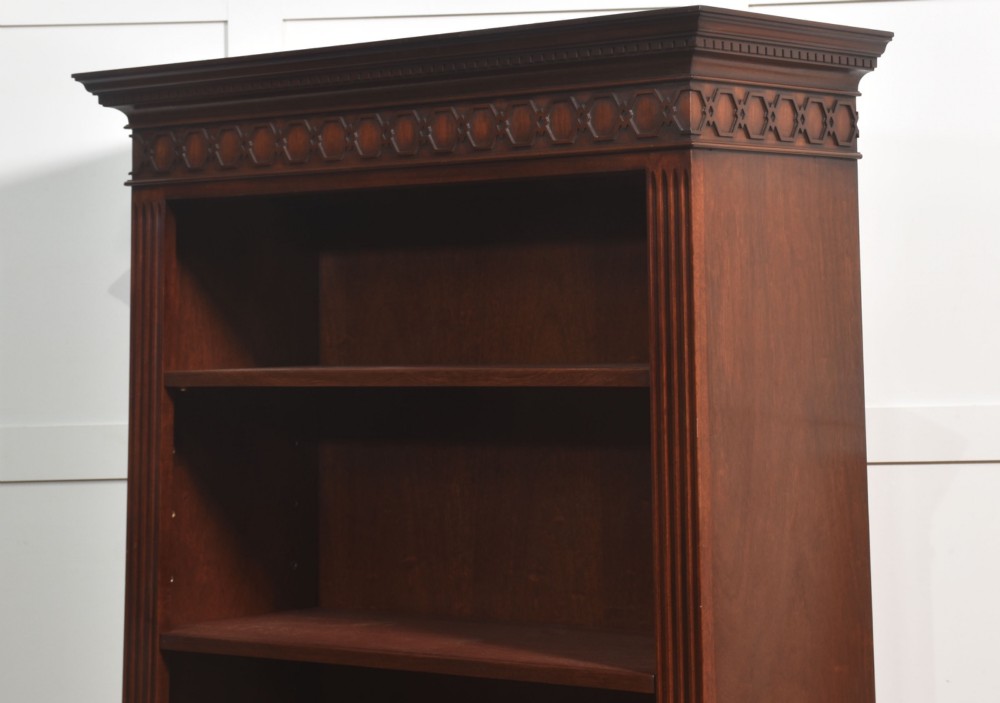 A tall mahogany open bookcase featuring adjustable shelves, fluted side pilasters, and a carved geometric frieze beneath a moulded cornice. View XI