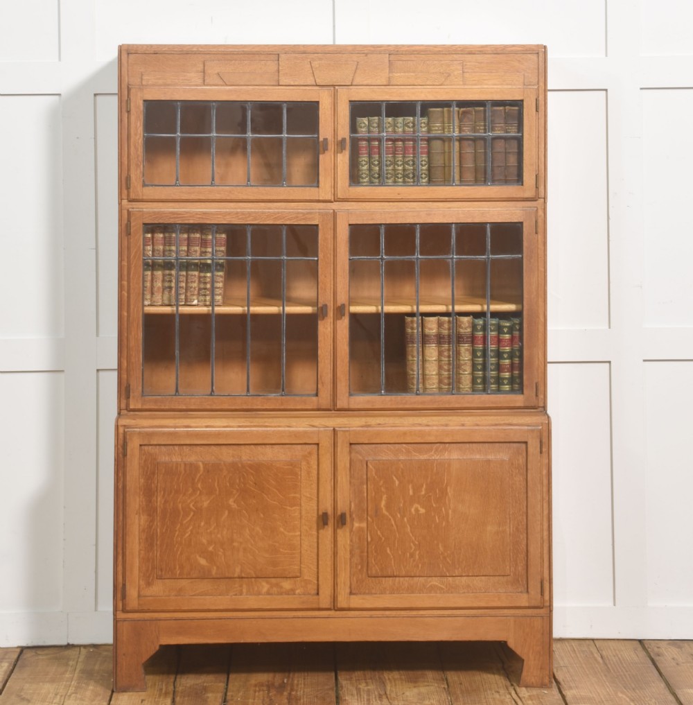 An Art Deco medium oak bookcase featuring two upper sections with leaded glass doors above a double-door base cupboard.