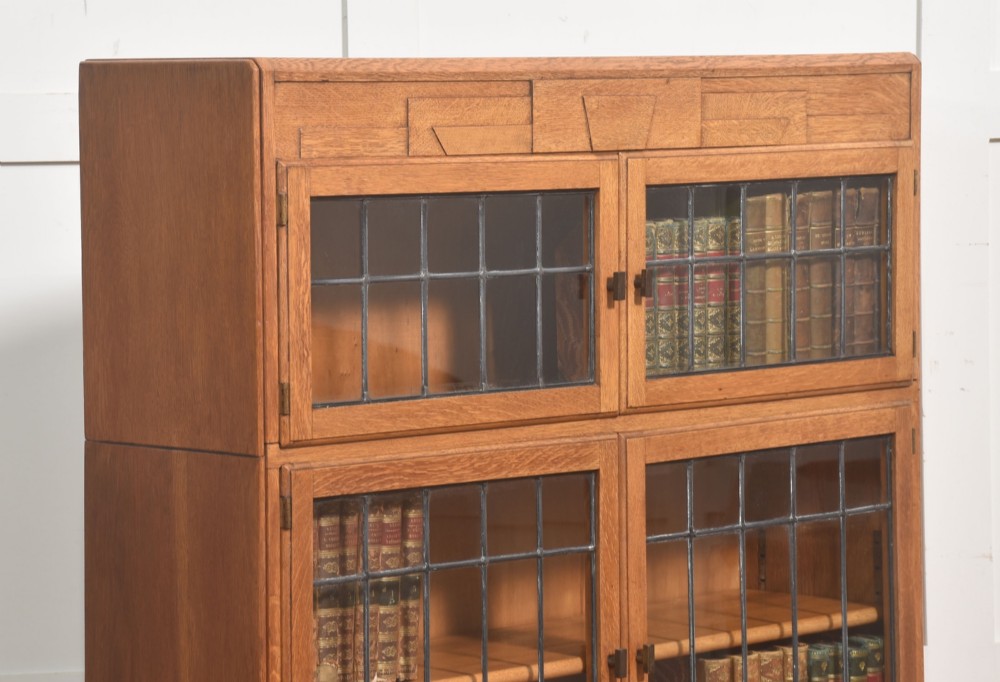 An Art Deco medium oak bookcase featuring two upper sections with leaded glass doors above a double-door base cupboard. View V