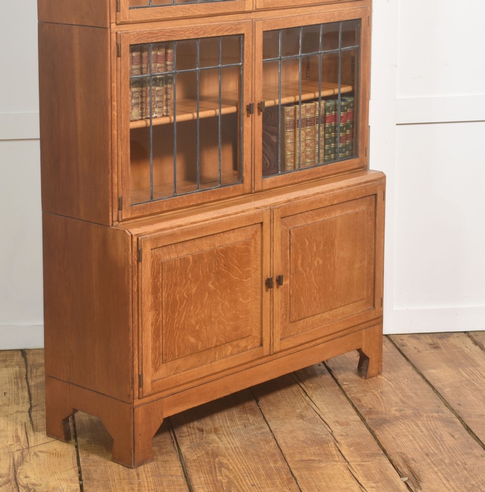 An Art Deco medium oak bookcase featuring two upper sections with leaded glass doors above a double-door base cupboard. View VI