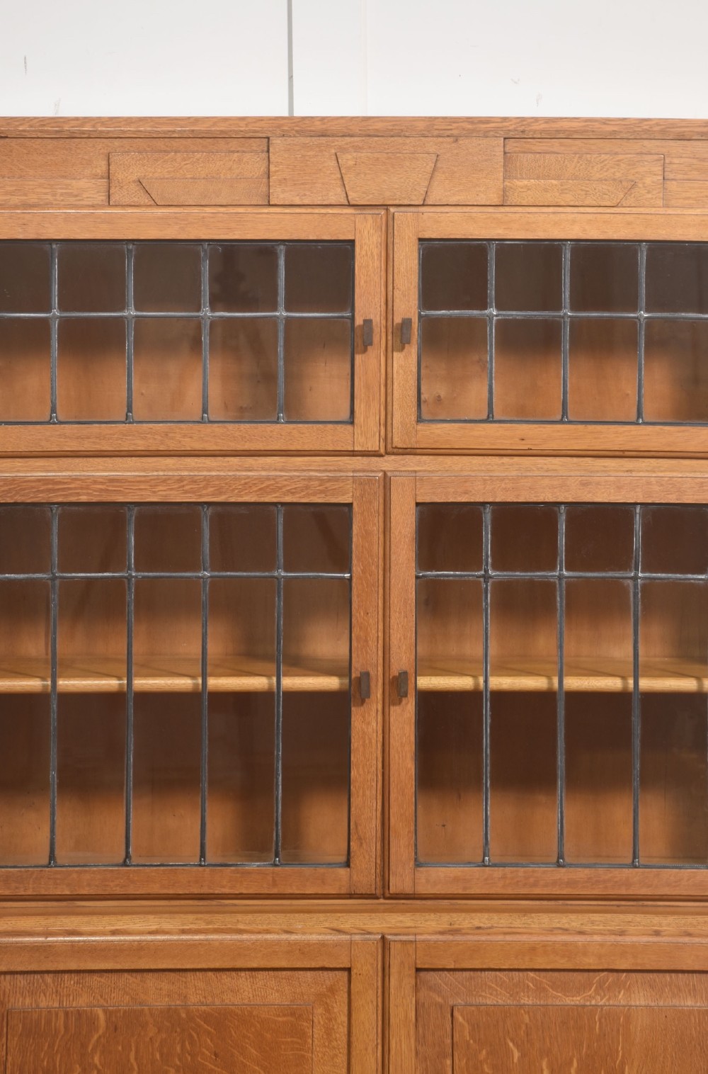 An Art Deco medium oak bookcase featuring two upper sections with leaded glass doors above a double-door base cupboard. View VIII