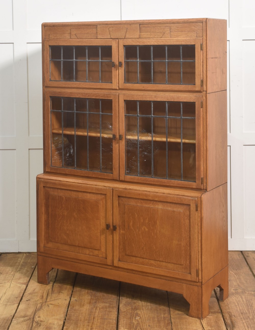 An Art Deco medium oak bookcase featuring two upper sections with leaded glass doors above a double-door base cupboard. View IX