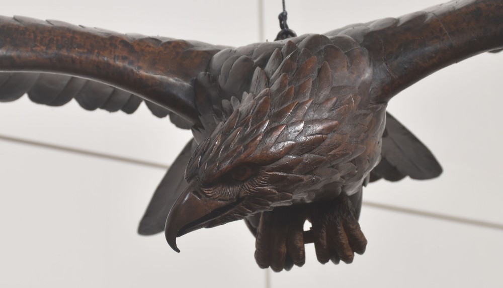 A dark wood eagle sculpture hand-carved in mid-flight with outstretched wings and carved feather detailing. View V