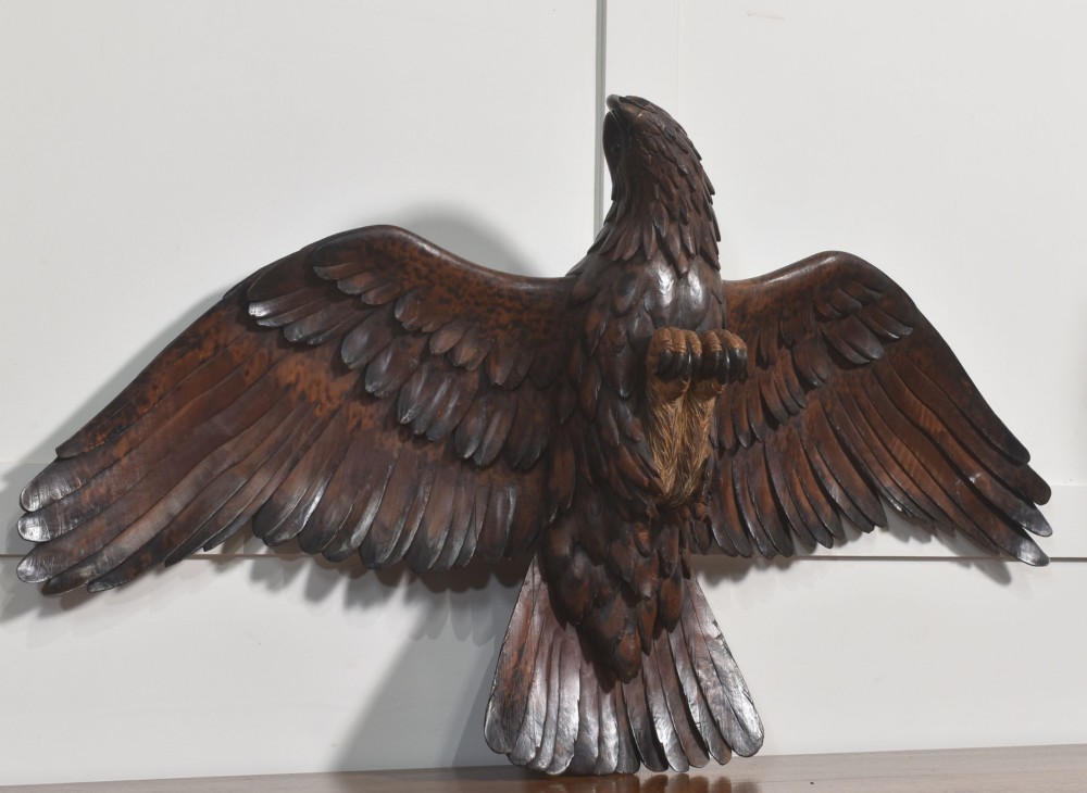 A dark wood eagle sculpture hand-carved in mid-flight with outstretched wings and carved feather detailing. View X