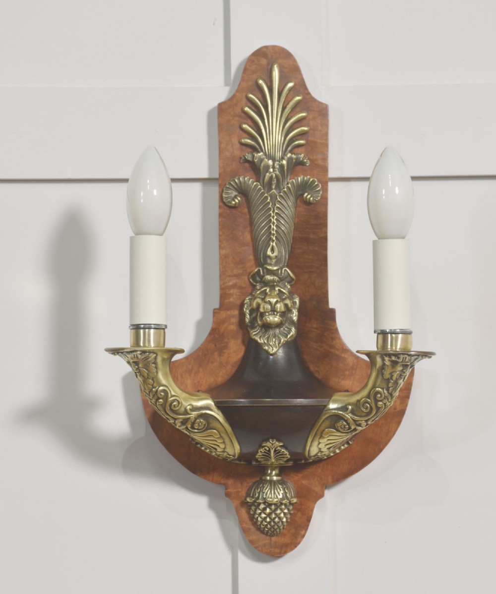 A pair of Empire style wall lights featuring shaped burr walnut backplates decorated with brass lion masks, anthemion crests, and twin scrolling candle arms. View III