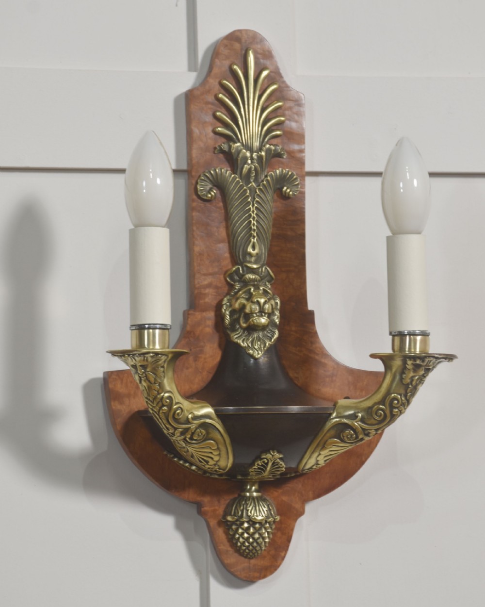 A pair of Empire style wall lights featuring shaped burr walnut backplates decorated with brass lion masks, anthemion crests, and twin scrolling candle arms. View IV