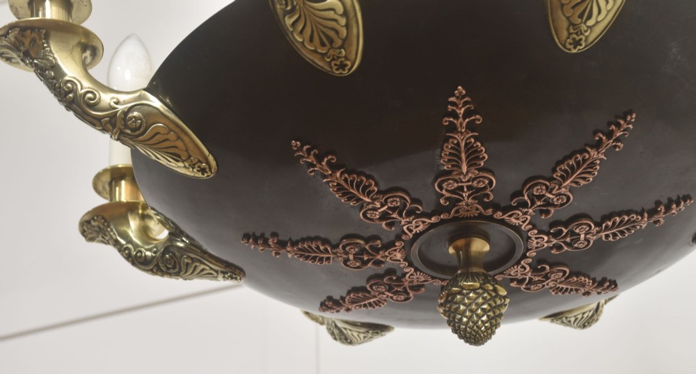 An Empire Revival brass and copper eight-light chandelier featuring a central dish supported by link chains and decorated with cast brass mounts and candle-style lights. View VI