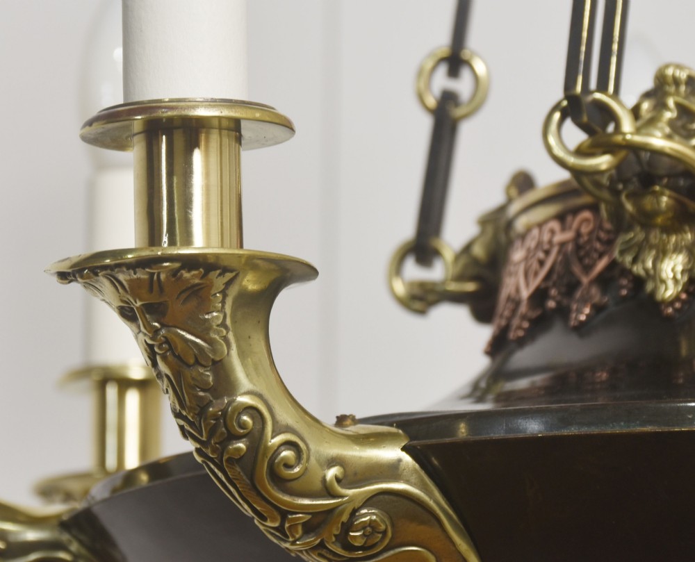An Empire Revival brass and copper eight-light chandelier featuring a central dish supported by link chains and decorated with cast brass mounts and candle-style lights. View IX