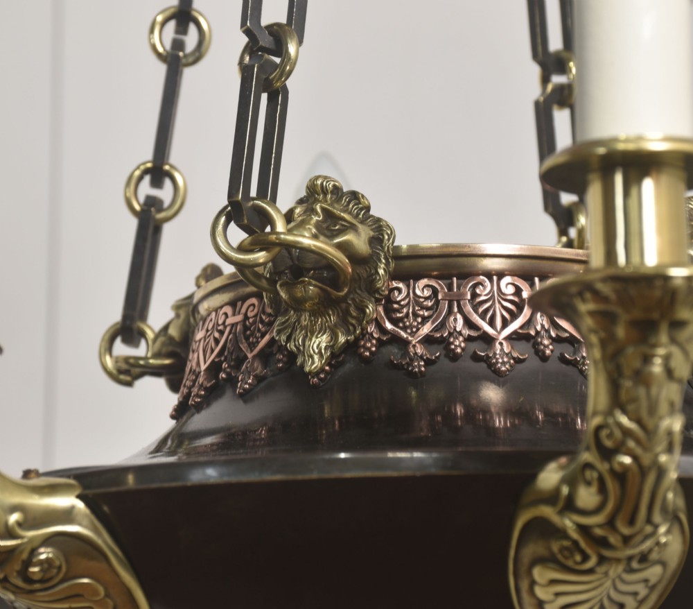 An Empire Revival brass and copper eight-light chandelier featuring a central dish supported by link chains and decorated with cast brass mounts and candle-style lights. View X