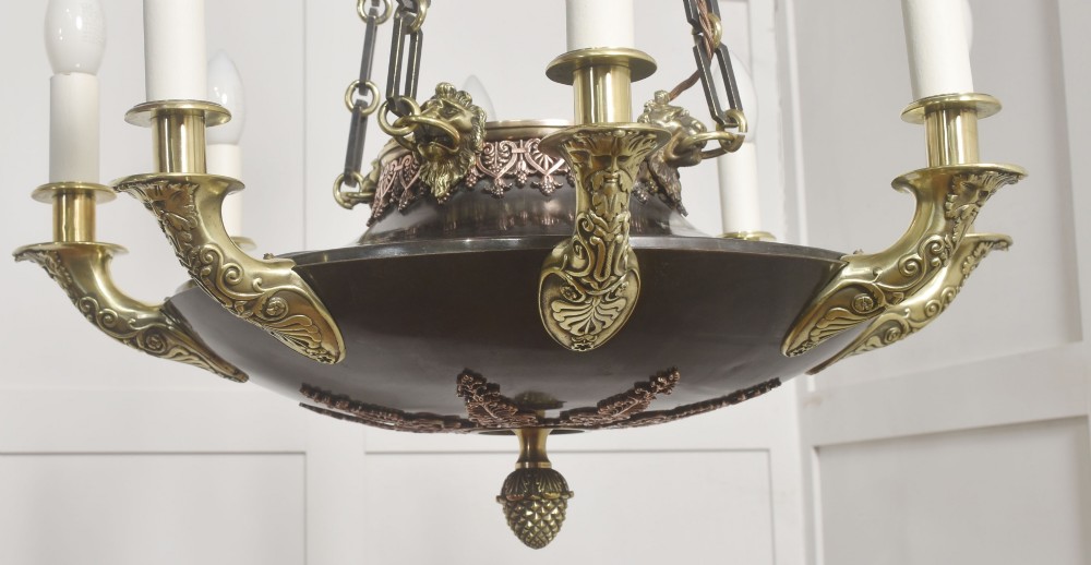 An Empire Revival brass and copper eight-light chandelier featuring a central dish supported by link chains and decorated with cast brass mounts and candle-style lights. View XI