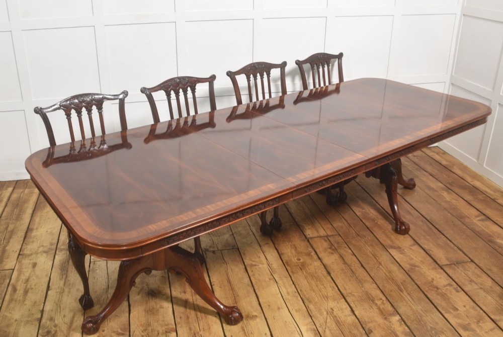 A large Chippendale revival mahogany extending dining table with a crossbanded top, carved frieze, and twin pedestal bases terminating in ball and claw feet. View III