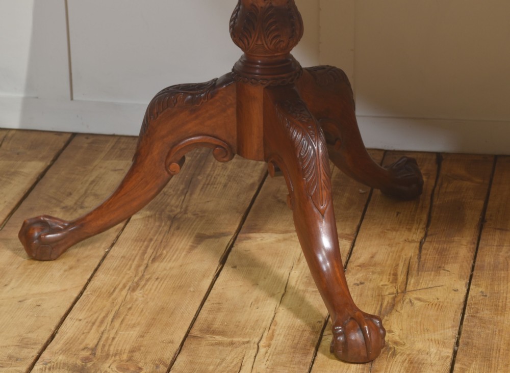 A large Chippendale revival mahogany extending dining table with a crossbanded top, carved frieze, and twin pedestal bases terminating in ball and claw feet. View VIII