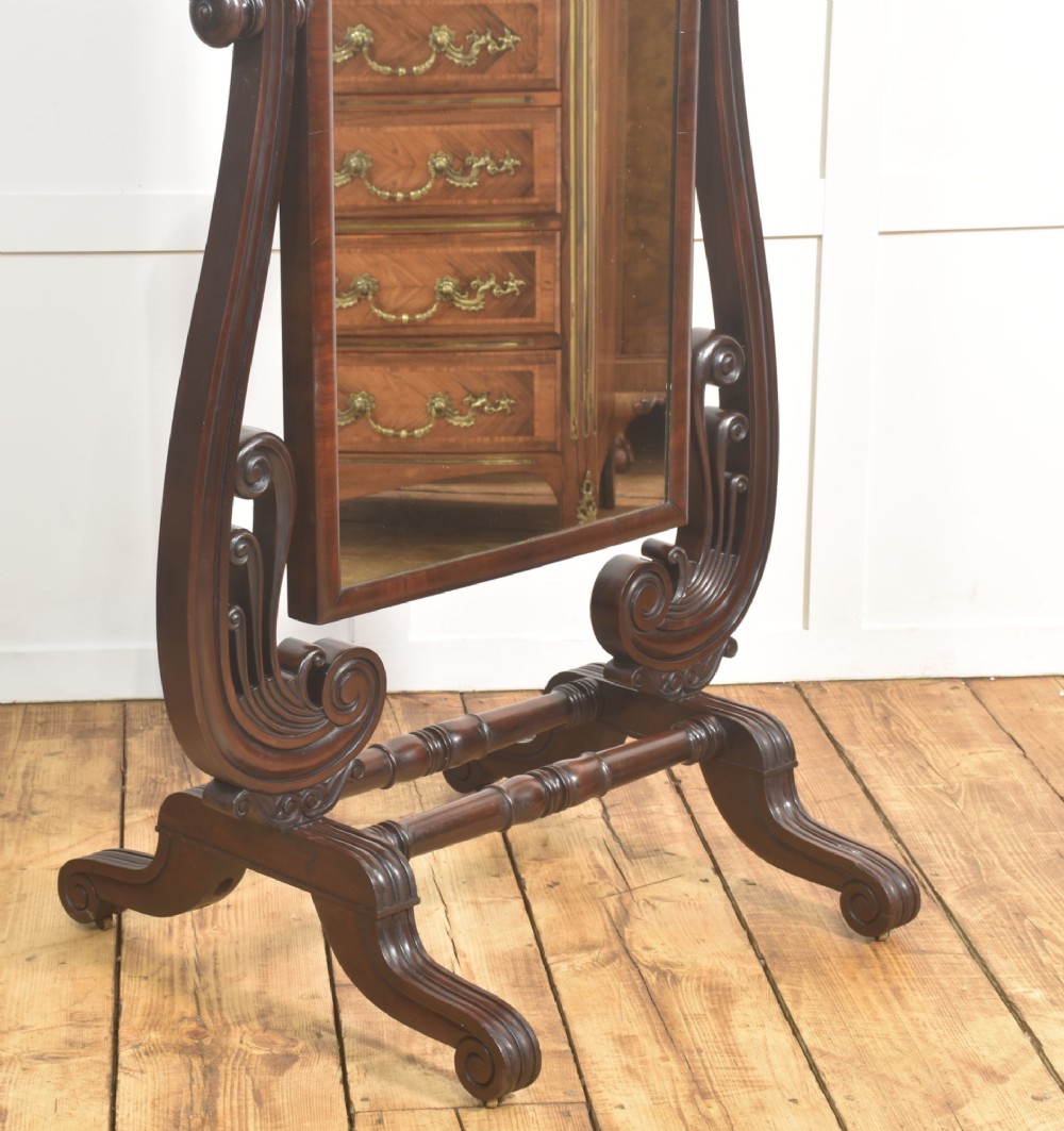 A William IV mahogany cheval mirror featuring carved scroll upright supports, a tilting full-length rectangular glass frame, and a stretcher base with swept feet. View III
