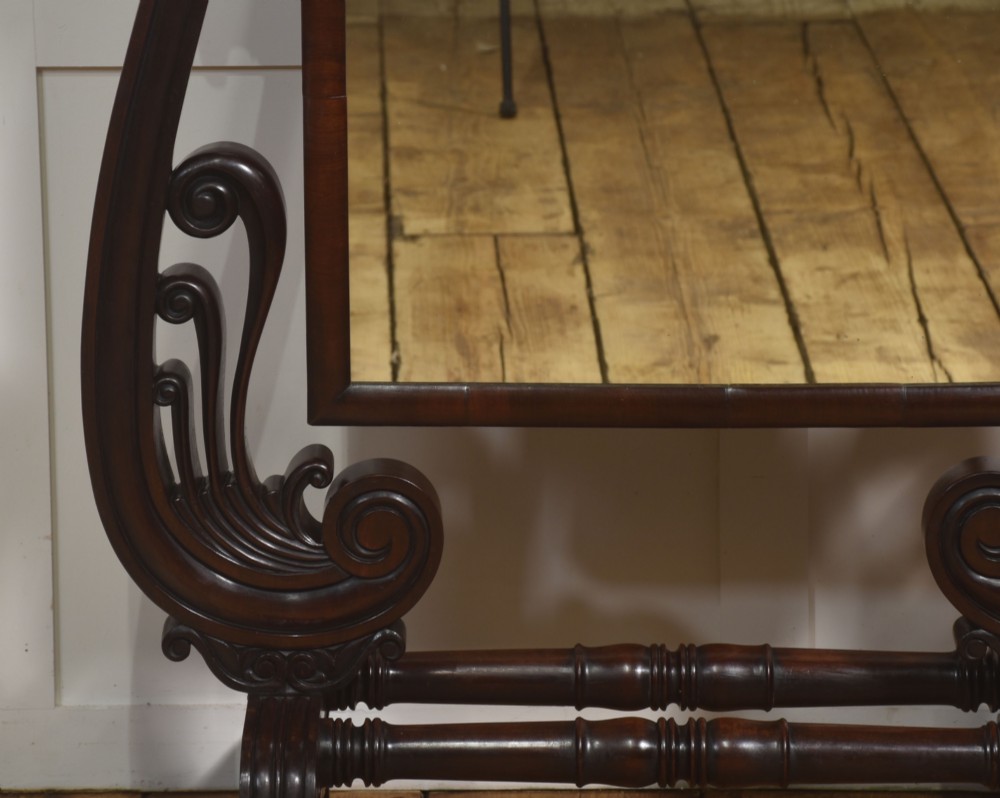 A William IV mahogany cheval mirror featuring carved scroll upright supports, a tilting full-length rectangular glass frame, and a stretcher base with swept feet. View VII