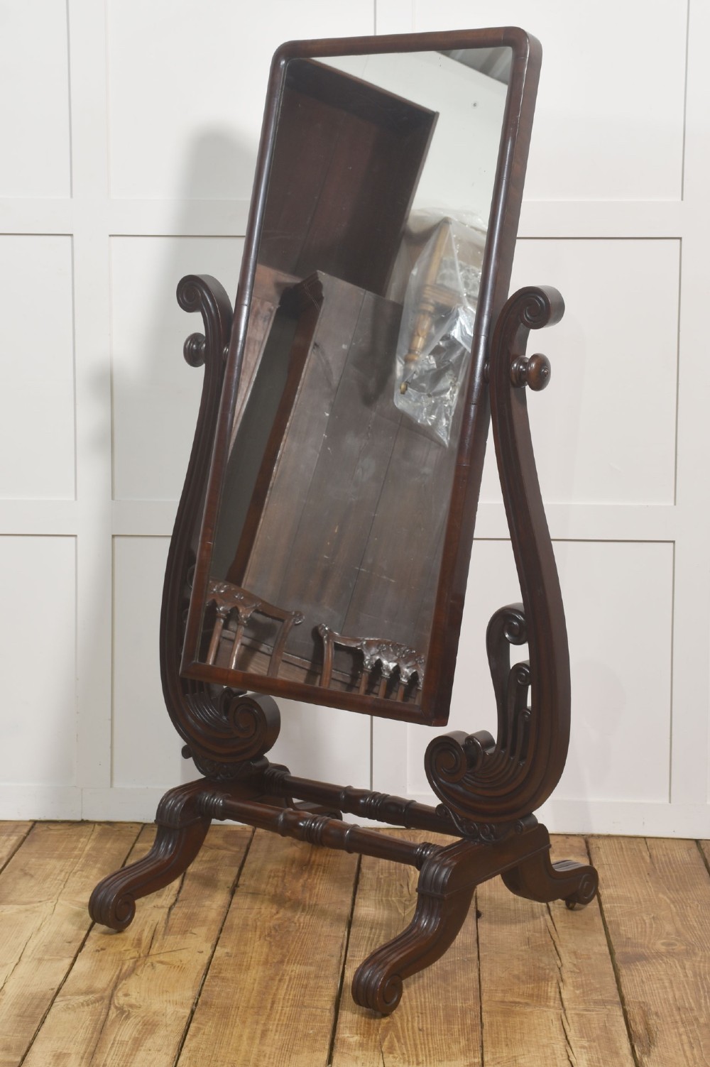 A William IV mahogany cheval mirror featuring carved scroll upright supports, a tilting full-length rectangular glass frame, and a stretcher base with swept feet. View VIII