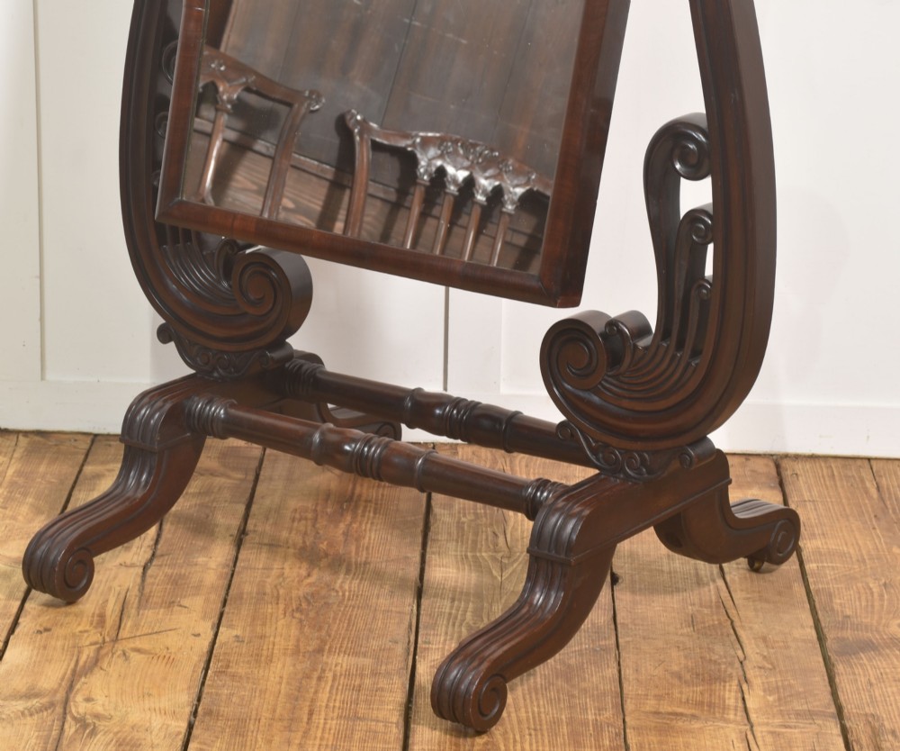 A William IV mahogany cheval mirror featuring carved scroll upright supports, a tilting full-length rectangular glass frame, and a stretcher base with swept feet. View IX
