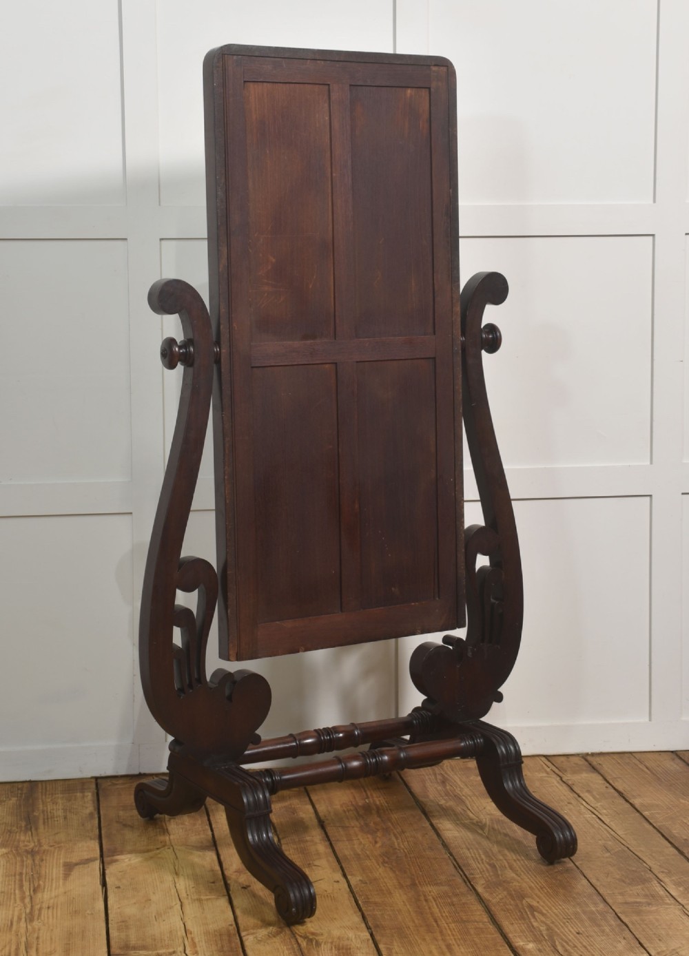 A William IV mahogany cheval mirror featuring carved scroll upright supports, a tilting full-length rectangular glass frame, and a stretcher base with swept feet. View X