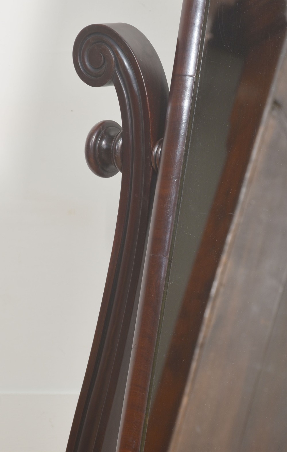 A William IV mahogany cheval mirror featuring carved scroll upright supports, a tilting full-length rectangular glass frame, and a stretcher base with swept feet. View XI