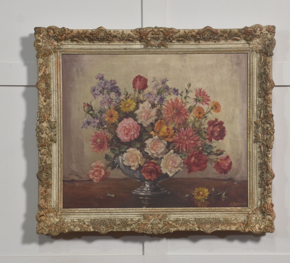 An oil painting on canvas depicting a colourful floral arrangement in a silver urn vase, set within a heavily carved gilt frame.