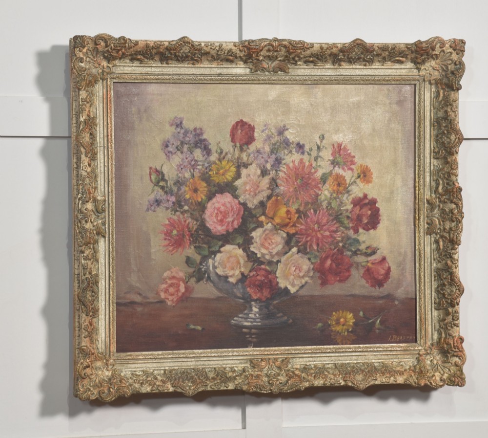 An oil painting on canvas depicting a colourful floral arrangement in a silver urn vase, set within a heavily carved gilt frame. View III