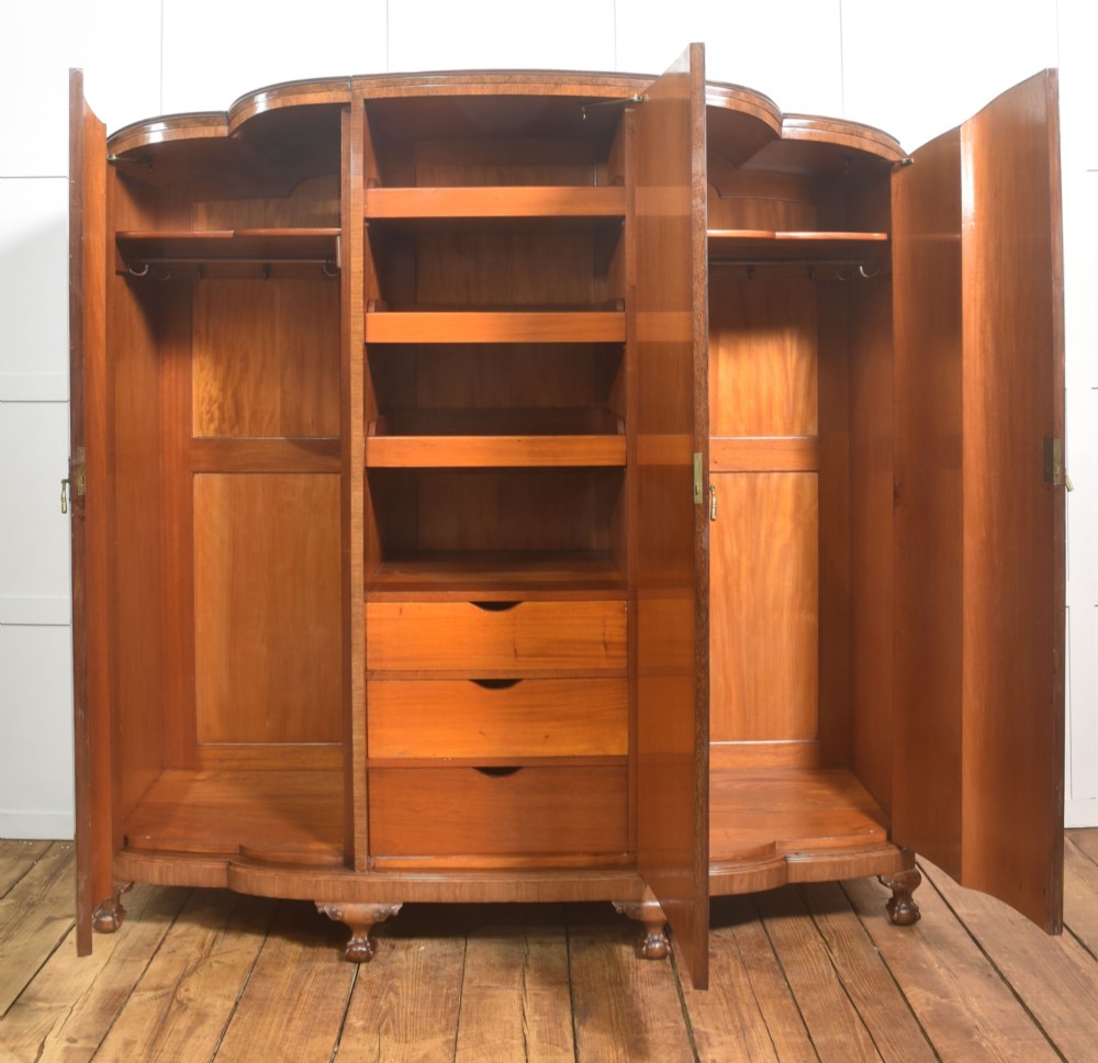 An Art Deco burr walnut breakfront wardrobe with curved side doors, a raised central door, and short carved feet. View IV